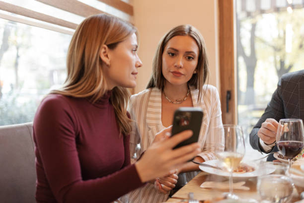 istock Two Women in a Restaurant Having Conversation and Showing Each Other Something on Mobile Phones 1846750579