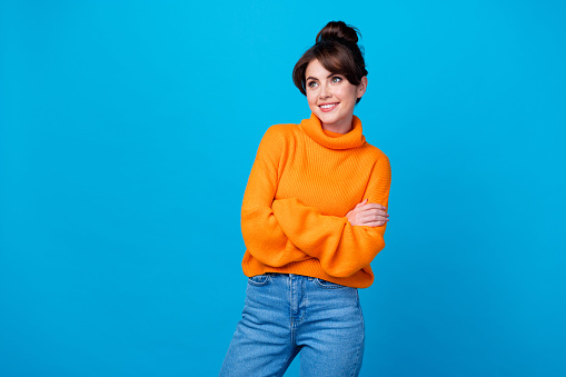 Photo of funky dreamy lady wear knitted pullover arms folded looking empty space isolated blue color background.