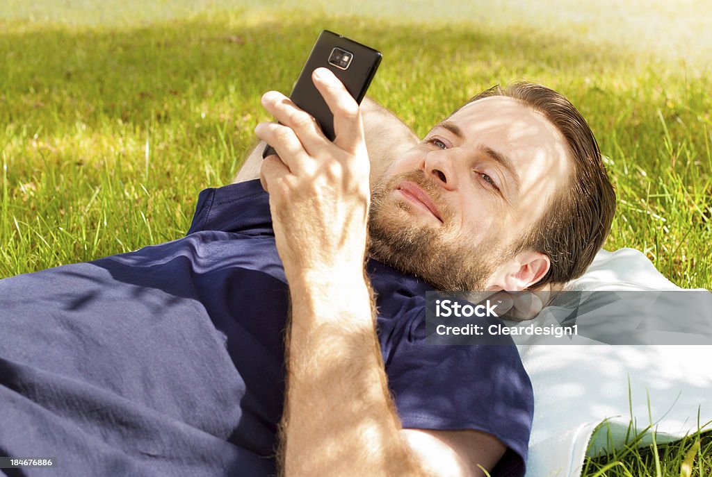 Homem feliz olhando para telemóvel ao pôr em relva - Royalty-free 40-44 anos Foto de stock