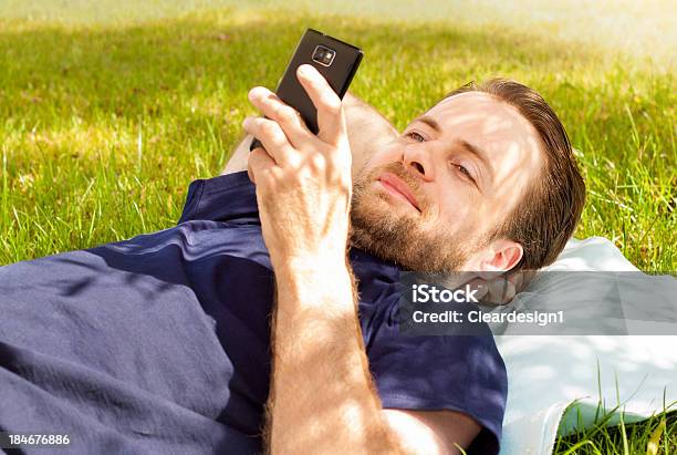 Счастливый Человек Глядя На Мобильный Телефон Лежал На Траве — стоковые фотографии и другие картинки 40-44 года