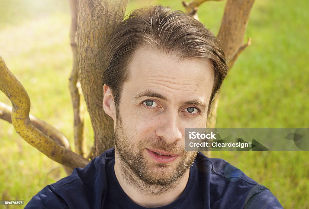 Heureux homme assis sur un arbre dans le parc, en plein air - Photo de 35-39 ans libre de droits