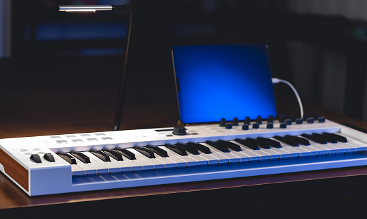 Musical keys and tablet in a dark room. Home music studio. Working with sound.