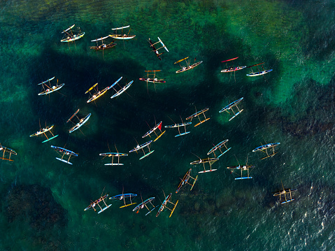 Aerial view of traditional oruwa boats with fishermen in tropical waters, showcasing local fishing methods and cultural heritage, surrounded by crystal-clear sea with outrigger canoes. Top view.
