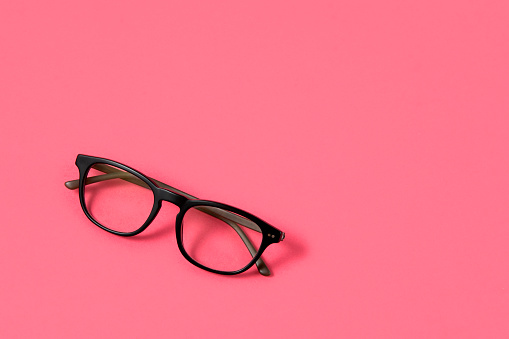 Eyeglass on pink background with copy space