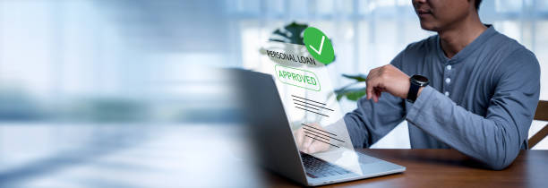 Man uses a computer to check approved personal loans from a bank or company that allows individuals or organizations to borrow money for business or personal expenses. Finance and investment