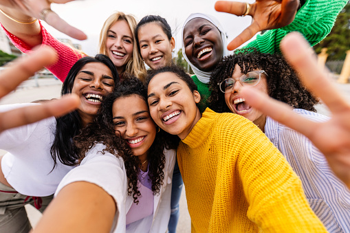 Multiracial young group of women having fun together taking selfie portrait. Joyful millennial teenage girls enjoying time together at city street. Female community and friendship concept.