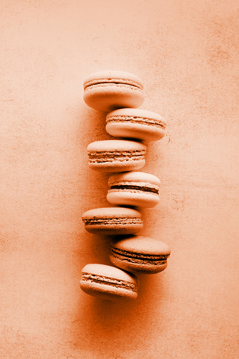 Color trend 2024: Peach Fuzz. French dessert colorful macaroons, minimal concept flat lay. Stack of macarons, macaroons French cookie , trendy color toning