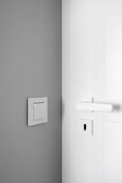 istock Light switch on gray wall close to white door with metal handle 1846839302