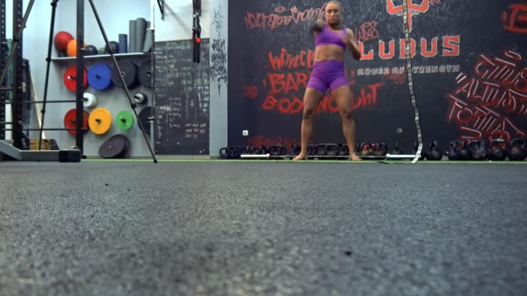 A video session at the gym, a tripod on the left side, an athletic woman working out