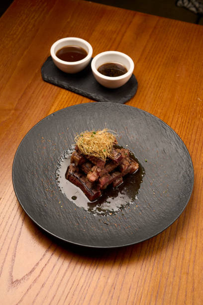 istock Grilled and sliced beef with sauce on a black plate, close-up 1846841461