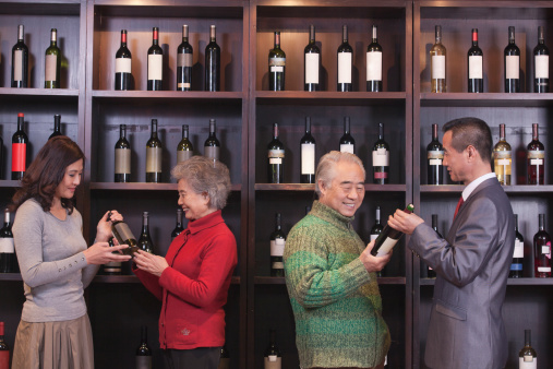 Four People Examining Wine Bottles at a Wine Store