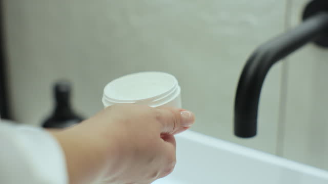 Close up of woman rubbing cream on her hand at bathroom. Soft skin hand, hand cream, hand skin care concept.