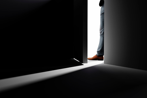 A man opens the door to a dark room.