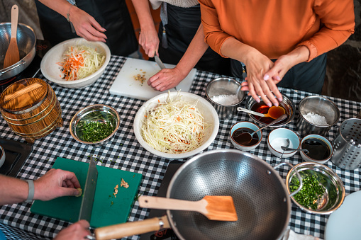 High-angle view of Chinese cuisine as they skillfully prepare ingredients for a flavorful vegetable stir-fry delight on a cooking class with beautiful Chinese female chefs.
