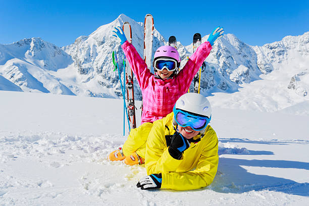 istock Two kids in bright snowsuits having fun skiing on the snow 184690555