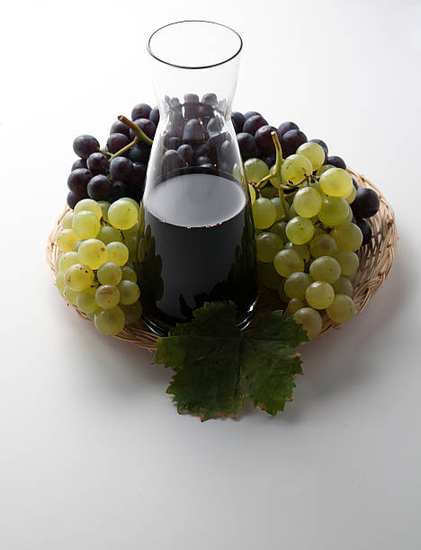Vinho Tinto em Licoreira e Prato cheio de uvas - fotografia de stock