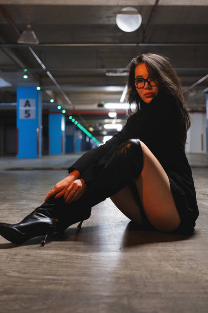 Young woman dressed in a trendy outfit leans against a garage door, showcasing her stylish yet relaxed attitude