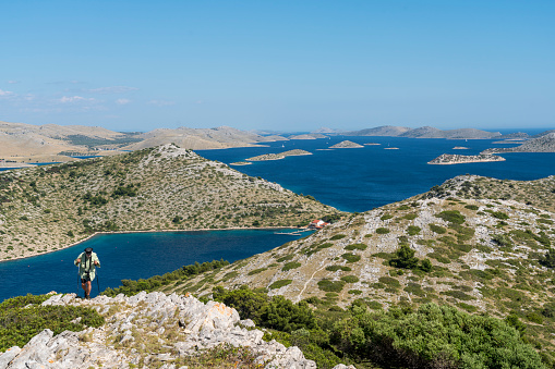Senior men moving up the hill with the view on Kornati islands from the top of island Lojena Sunny day, clear blue sky.