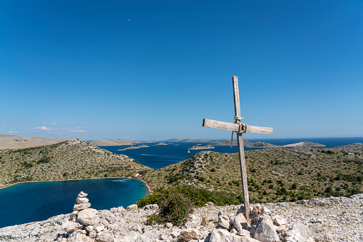 View on Kornati islands from the top of island Lojena Sunny day, turquoise bay, wooden cross, clear blue sky.