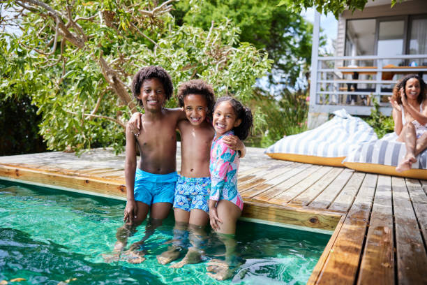 istock Smiling children standing in a pool with their mom watching in summer 1846932717