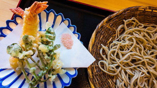 A top-down view of a traditional style Japanese cold soba dish with a side of prawn and vegetable tempura.