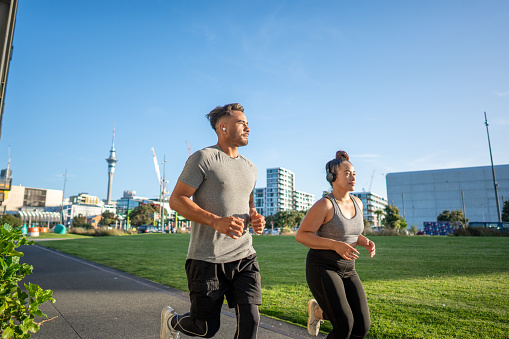 Young male and female Maori individuals running through Auckland City