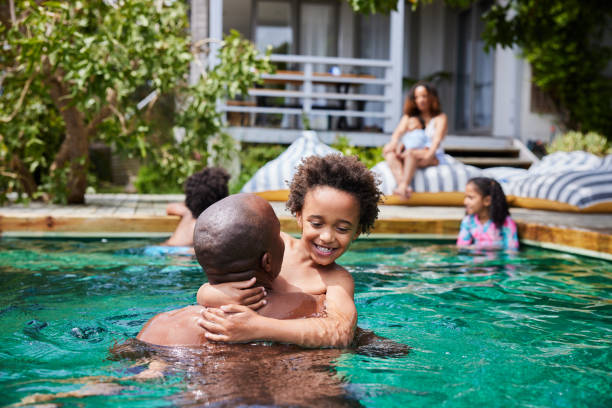 istock Dad playing with his little children in a pool with their mom watching 1846943821