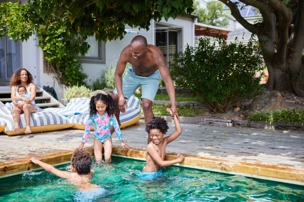 istock Dad playing with his children by a pool with their mom watching in summer 1846948167