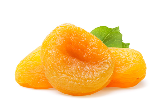 A pile of dried apricots with a leaf close-up on a white background. Isolated