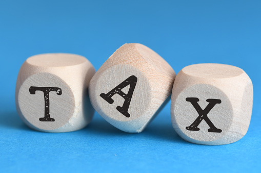 TAX text on wooden cubes on the blue background. Tax Business Concept .