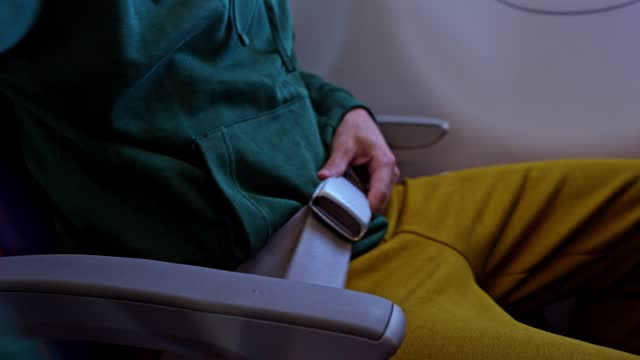 Young Man Fastening His Seatbelt In An Airplane