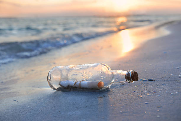 Message in a glass bottle on a beach at sunset stock photo