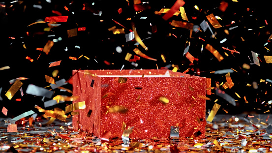Red gift box exploding with confetti against black background.