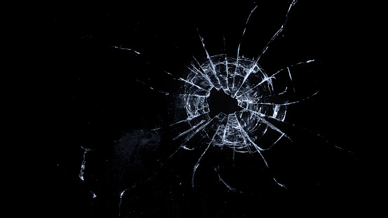 Silhouette of a girl looking at her phone distorted by broken glass.