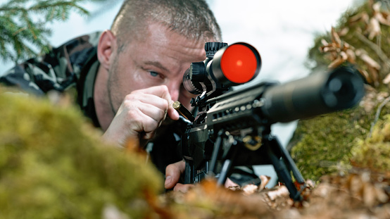 Close-up of soldier firing machine gun during battle in forest.