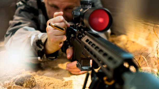 View of soldier firing machine gun during battle on desert landscape.