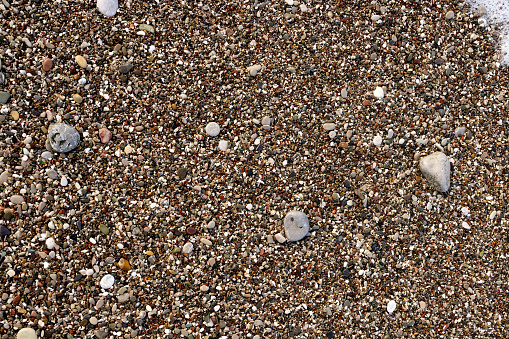 Rounded small pebbles with rare large quartz pebbles on the beach in Montenegro