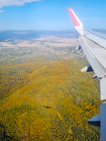 View of green hills in Serbia from the airplane window mid-air.