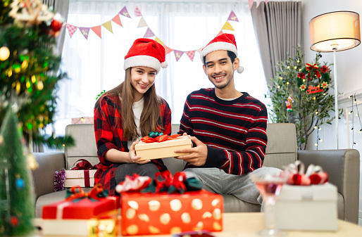 Asian young woman getting surprise gift from her girlfriend at home. Gives a Christmas gift, birthday gift, New year day celebration
