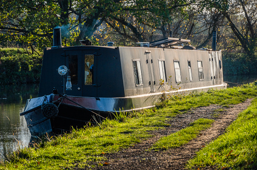 This is a narrow boat houseboat barge moored on the canal waterway nr. Stratford upon Avon. It is a warm sunny day in autumn and there are no visible people in the picture.