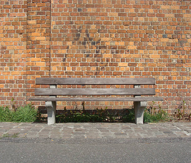 istock wooden bench with path in front of a brick wall 184706442