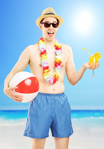 istock Smiling male holding a ball and cocktail, on beach 184706840