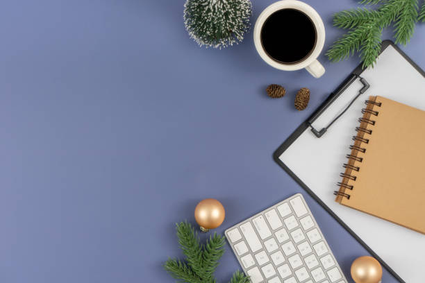 istock Office desk table with computer keyboard, paper clipboard, notepad, cup of coffee and Christmas decorations on pastel blue background. 1847079174