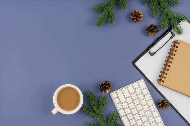 istock Office desk table with computer keyboard, paper clipboard, notepad, cup of coffee and Christmas decorations on pastel blue background. 1847079695