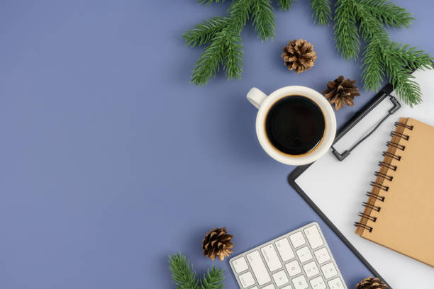 istock Office desk table with computer keyboard, paper clipboard, notepad, cup of coffee and Christmas decorations on pastel blue background. 1847080010