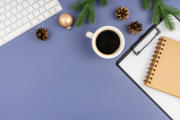 istock Office desk table with computer keyboard, paper clipboard, notepad, cup of coffee and Christmas decorations on pastel blue background. 1847080222
