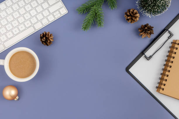 istock Office desk table with computer keyboard, paper clipboard, notepad, cup of coffee and Christmas decorations on pastel blue background. 1847080280