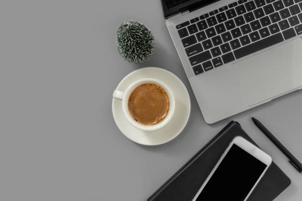istock Office desk table with laptop, mobile phone, notepad, cup of coffee and Christmas tree on gray background. 1847080827