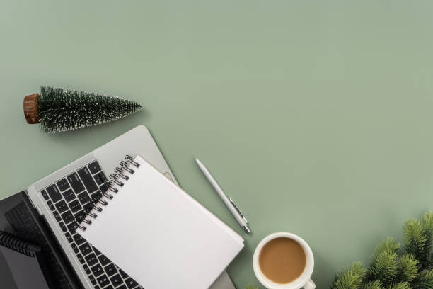 istock Office desk table with laptop, notepad, cup of coffee and Christmas tree on pastel green background. 1847080877