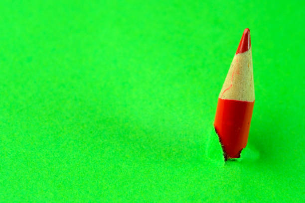 Small pencil breaking through green paper ストックフォト